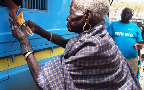 Teko Okudo recieving money from the mobile bank van in Moroto